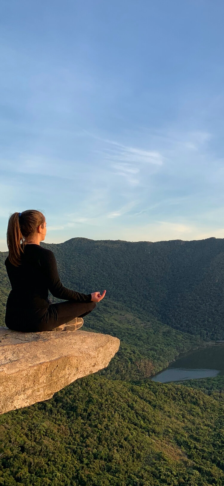 Pedra da lagoinha do leste com pessoa sentada meditando e vista das montanhas e pedras ao fundo